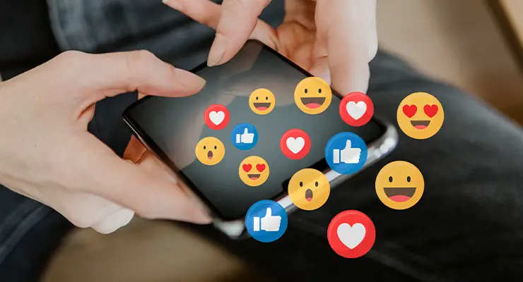 Person holding a smartphone, surrounded by floating social media reactions like likes, hearts, and emojis.